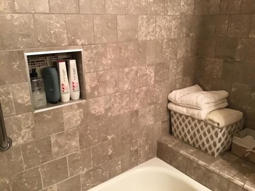 a bathroom with a tub and a shelf with towels at Clovis, CA National Parks Room in Clovis
