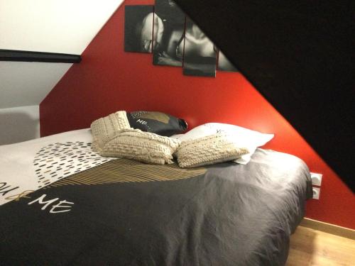 Un dormitorio con una cama con una pared roja. en Détour d’un soir…, en Saint-Inglevert