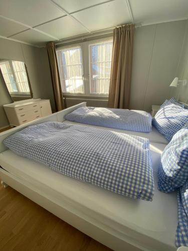 a bedroom with two beds with blue and white sheets at Familienferien im Chalet Bärgli Kandersteg in Kandersteg