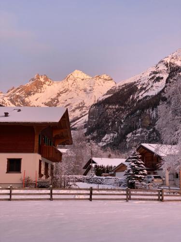 a building with snow covered mountains in the background at Familienferien im Chalet Bärgli Kandersteg in Kandersteg