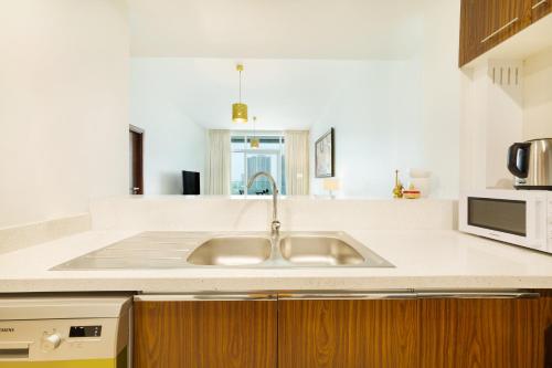 eine Küche mit einer Spüle und einer Mikrowelle in der Unterkunft Maison Privee - Superb 1BR apartment overlooking Zabeel Park and Dubai Frame in Dubai