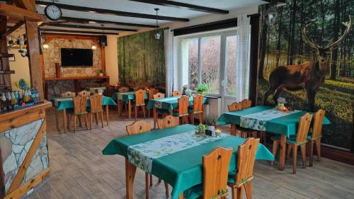 restauracja z zielonymi stołami i łosiem na ścianie w obiekcie Oberża KNIEJÓWKA w mieście Załom