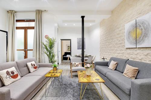 a living room with two couches and a brick wall at Beautiful flat in the heart of the Marais in Paris