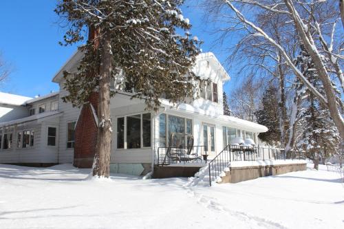 une maison blanche avec de la neige au sol dans l'établissement Tally Ho Inn, à Huntsville