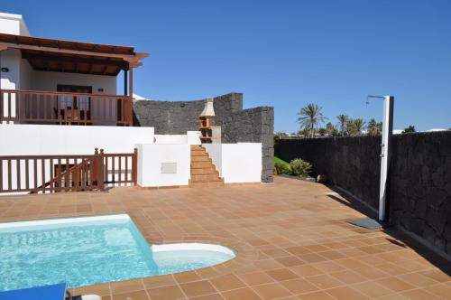 un patio trasero con piscina y una casa en Villa Esmeralda en Playa Blanca