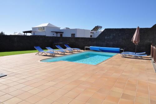 a swimming pool with lounge chairs and an umbrella at Villa Esmeralda in Playa Blanca