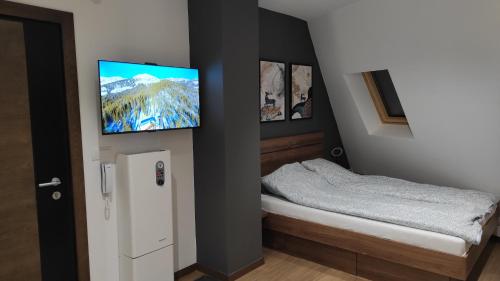 een slaapkamer met een bed en een flatscreen-tv aan de muur bij Dva Jelena in Divčibare