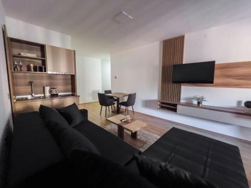 a living room with a black couch and a table at Hany Sweet in Niš