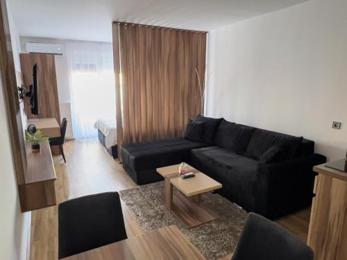 a living room with a black couch and a table at Hany Sweet in Niš