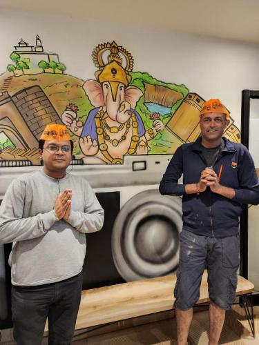 two men wearing orange hats standing in front of a washing machine at Coliwo Un - Viman Nagar in Pune