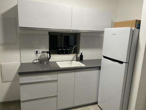 a white kitchen with a sink and a refrigerator at פסגת יובלים in Qiryat Shemona