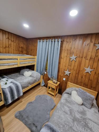 Duas camas num quarto com painéis de madeira em Serra da Estrela Guest House em Covilhã