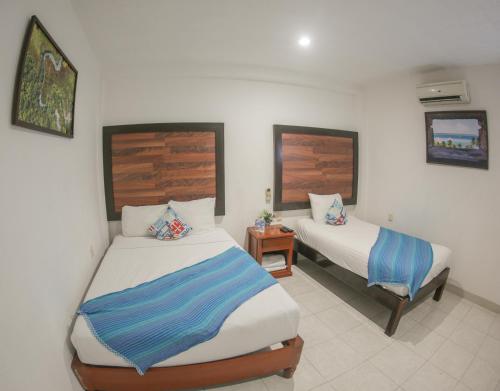 1 dormitorio con 2 camas y mesa con mesita de noche en Seven Blue House Village & Lodge, en Bacalar