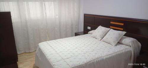 a bedroom with a large white bed with a wooden headboard at Piso Estación in Silleda