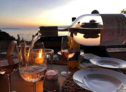 a bottle of wine is being poured into wine glasses at Villa „Sorbier“ mit Pool/ Meerblick an Côte d’Azur in Rayol-Canadel-sur-Mer