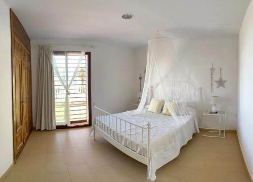 um quarto com uma cama de dossel branca em Villa Los Pinares de Monaco en Roche, Conil, Cádiz em Conil de la Frontera