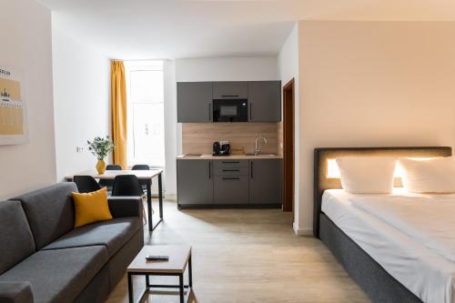 ein Hotelzimmer mit einem Bett und einem Sofa sowie einer Küche in der Unterkunft Homaris Boxi Studios in Berlin