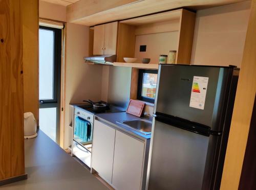 una pequeña cocina con refrigerador y fregadero en Departamento dos ambientes, muy cálido y luminoso, en el centro de SMA. 17V5 en San Martín de los Andes