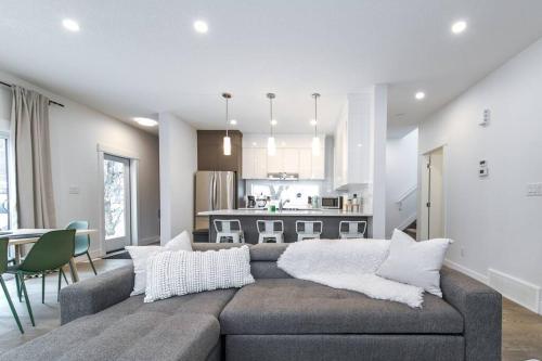 a living room with a couch and a kitchen at Chic Hideaway, 5BR near DT, Fireplace, King Bed, Fast Wifi, Sleeps 13! in Edmonton