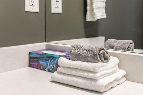 a pile of towels sitting on a counter in a bathroom at Chic Hideaway, 5BR near DT, Fireplace, King Bed, Fast Wifi, Sleeps 13! in Edmonton