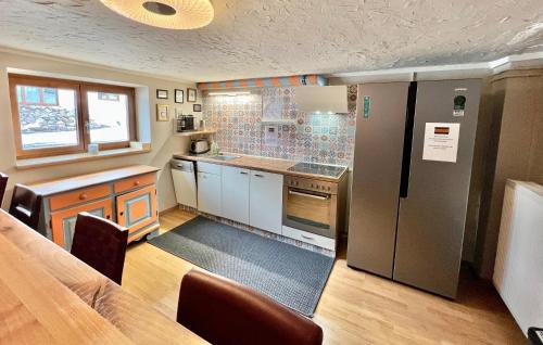 eine Küche mit einem Kühlschrank aus Edelstahl und einem Tisch in der Unterkunft Lech Hostel in Lech am Arlberg