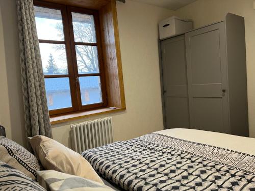 Schlafzimmer mit einem Bett und einem Fenster in der Unterkunft Maison rénovée au cœur du Haut-Jura in Entre-Deux-Monts