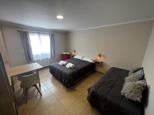 a bedroom with two beds and a desk and a table at Hosteria Yamile in El Calafate