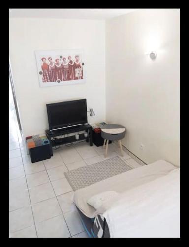 Habitación blanca con cama y TV en T1 proximité de Montpellier., en Juvignac