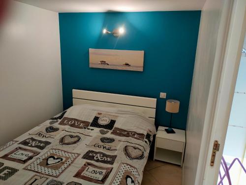 une chambre avec un mur bleu et un lit dans l'établissement T2 rez-de-jardin Piscine 3x5m près d'Arcachon, à La Teste-de-Buch