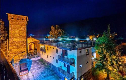 a large white building with a tower at night at Guesthouse David Zhorzholiani in Mestia