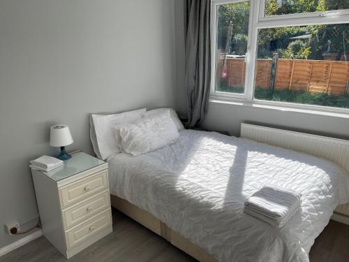 a bedroom with a bed with a night stand and a window at Entire Lovely 2 bedroom apartment with private garden & free street parking in London