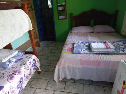 a bedroom with two beds and a green wall at Pousada Cajueiro in Itaúnas