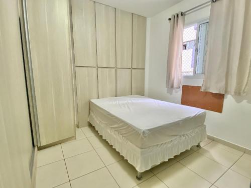 une chambre blanche avec un lit et une fenêtre dans l'établissement F034 - Apto no Forte Churrasqueira, Wi-Fi e Piscina, à Praia Grande