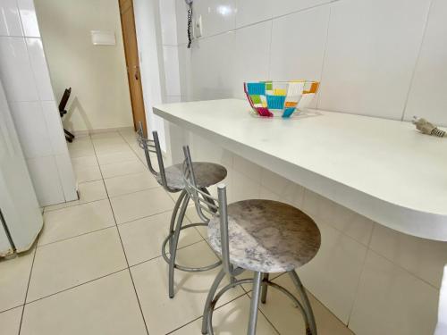 une cuisine avec un comptoir et deux tabourets dans l'établissement F034 - Apto no Forte Churrasqueira, Wi-Fi e Piscina, à Praia Grande