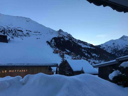 a building covered in snow next to a mountain at Studio skis au pieds Meribel-Mottaret in Les Allues