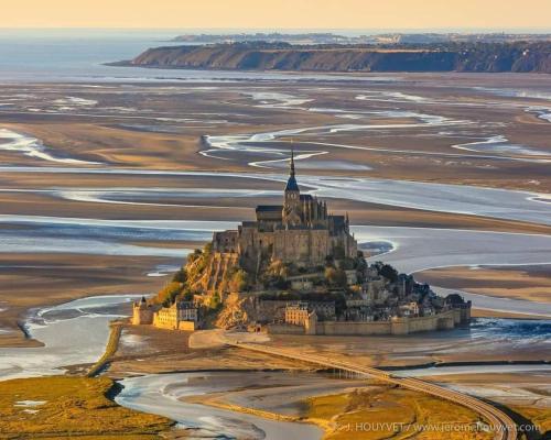 un château sur une île au milieu d'un champ dans l'établissement Gîte Mont Saint Michel Beauvoir, à Beauvoir