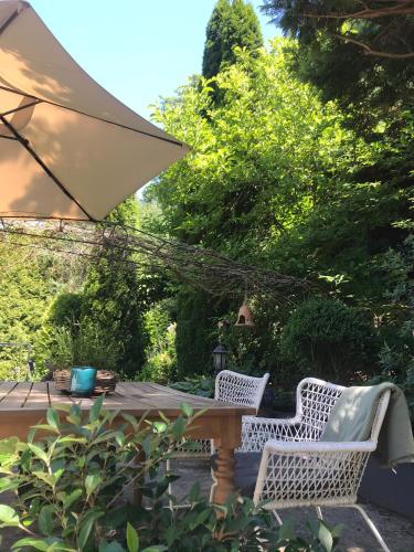 two white chairs and a table with an umbrella at Willa Urocze in Muszyna