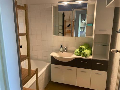 ein Badezimmer mit einem Waschbecken, einer Badewanne und einem Spiegel in der Unterkunft Weinapartment St. Urban in Sankt Urban