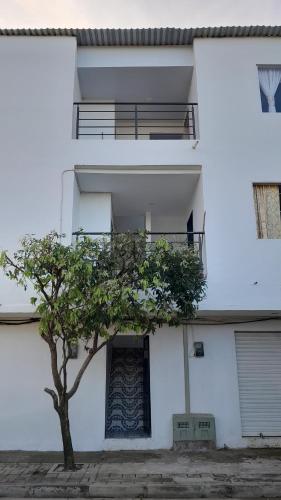 a white building with a tree in front of it at Apartamento Esmeralda Arboletes in Arboletes