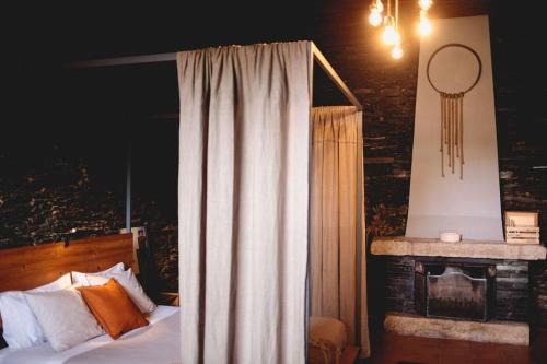 ヴァロンゴにあるPorto Natura Loftのベッドルーム1室(カーテン付きのベッド1台、暖炉付)