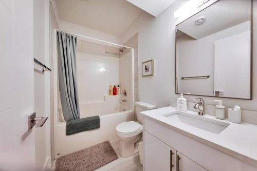 a white bathroom with a sink and a toilet at Chic Retreat, 4BR Near DT & WEM, Fireplace, Trails, Sleeps 10! in Edmonton