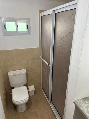 baño con aseo y puerta de ducha de cristal en Casa Las Moras en San Antonio de Arredondo