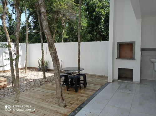 a patio with a table and chairs and trees at Casa geminada 2 no Mariscal in Bombinhas