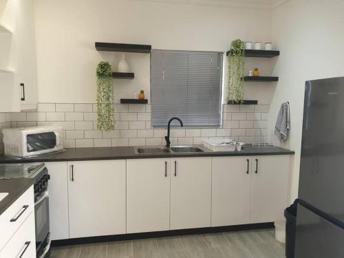 a kitchen with white cabinets and a sink at Overnight stay. Self-catering. in Klerksdorp