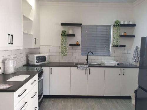 une cuisine avec des placards blancs et un comptoir noir dans l'établissement Overnight stay. Self-catering., à Klerksdorp