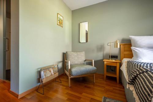 a bedroom with a chair and a bed and a desk at Boutique Hotel Bellevue Lermoos in Lermoos
