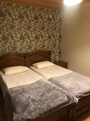 two beds in a bedroom with floral wallpaper at Guesthouse David Zhorzholiani in Mestia