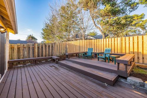 a wooden deck with benches and tables in front of a fence at Seas The Day in Seaside