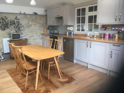 a kitchen with a wooden table and chairs in it at Secret little hideaway - with proximity to Oxford in Cassington