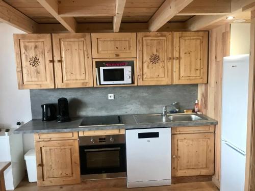 cocina con armarios de madera, fregadero y microondas en appartement ski au pied, en Les Deux Alpes